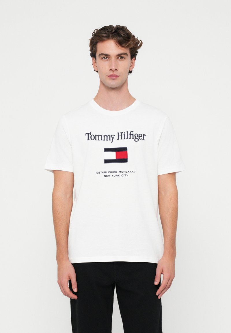 Hvid bomulds T-shirt med "Tommy Hilfiger" logo og flag grafik i rød, blå og hvid. Korte ærmer og rund hals design.