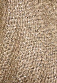 Goldfarbener Paillettenstoff mit strukturierter Oberfläche, der eine dichte Anordnung glänzender silberner Pailletten aufweist und einen schimmernden Effekt erzeugt.