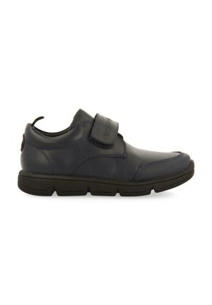 Zapato de cuero azul marino con puntera texturizada, correa de velcro y suela de goma negra. Presenta detalles de costura y una lengüeta en el talón.