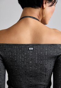 Šedý žebrovaný top bez ramen, vyrobený z texturovaného materiálu s malou nášivkou "Moschino Jeans" na zadní straně.