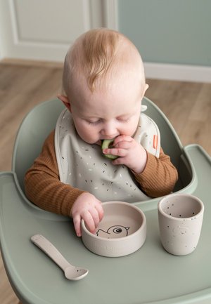 Bowl, cup, and spoon set in soft beige. Bowl features a bird illustration; textured finish; silicone bib. Circular design for easy grip.