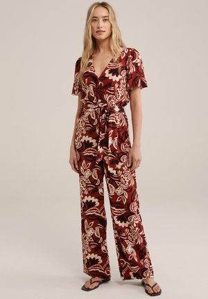Röd blommig jumpsuit med korta ärmar, V-ringning, vida ben och knytmidja. Har djärva creamfärgade och svarta blommönster.