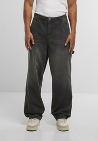 Zwarte baggy denim jeans met een hoge taille, vijf zakken en een knoopsluiting. Gekocht met witte en crèmekleurige sneakers met een gestructureerde zool.