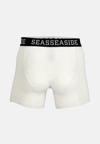 Boxer in cotone bianchi con un elastico nero in vita, su cui è stampato "SEASIDE" in bianco. Texture liscia, design attillato.