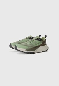 Chaussures de plein air vertes avec une tige en mesh, des superpositions texturées, des semelles robustes et un talon renforcé. Accents en noir et gris clair.