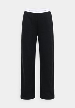 Pantalons de survêtement noirs en tissu doux, dotés d'un design à jambe large et d'une taille élastique blanche avec le logo "Calvin Klein".