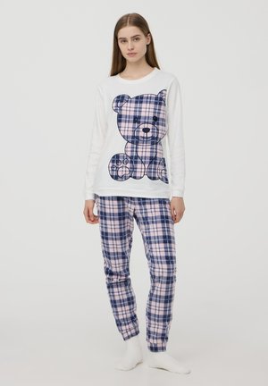Maglietta bianca a maniche lunghe con grafica di un orso, abbinata a pantaloni da pigiama a quadri rosa e blu scuro. Tessuto morbido, vestibilità comoda e girovita elastico.