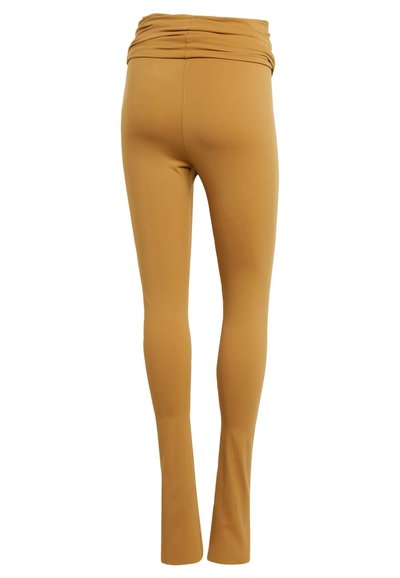Rekbare, mosterdgele leggings met een hoge, geraffineerde tailleband. Strakke textuur, aansluitende pasvorm en uitlopende pijpen. Geen zichtbare patronen of hardware.