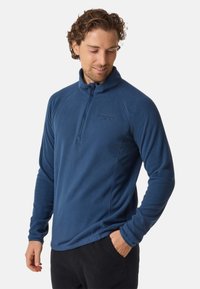 Pullover in pile blu con mezza zip, dotato di un colletto alto e sobria cucitura del logo. Tessuto morbido e design aderente, adatto per essere indossato a strati.