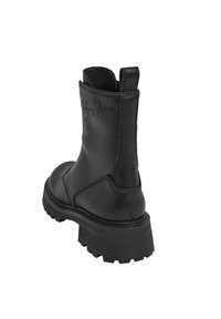 Zwarte leren enkellaars met een chunky zool, gestikte details en een trekriem; heeft een debosserend logo aan de buitenkant.