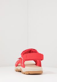 Sandalo sportivo rosso con cinturini regolabili, suola imbottita e suola esterna in gomma testurizzata per una buona aderenza. La vista posteriore evidenzia il design dei cinturini.