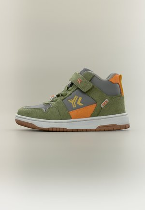 Wysokie sneakersy z zielonego zamszu, szare panele, pomarańczowe akcenty, pasek na rzep i biała podeszwa z brązowym bieżnikiem na neutralnym tle.