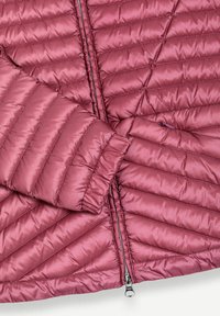 Close-up van een donkerrode gewatteerde pufferjas met horizontale stiksels, waarbij de mouw en ritssluiting te zien zijn met een glanzende stoftextuur.