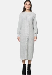 Vestito a maglia grigio con maniche lunghe a sbuffo, caratterizzato da un motivo centrale a treccia e orlo a coste, indossato con stivali neri alla caviglia.
