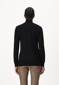 Svart genser med høy hals og lange ermer, laget av mykt materiale. Har ribbestrikkede mansjetter og nederkant, tettsittende design og glatt tekstur.