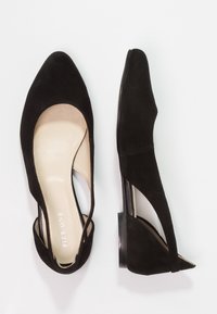 Schwarze Wildleder-Ballerinas mit spitzen Zehen, offenen Seiten und flachen Absätzen. Innenfutter aus weichem Beige, das ein schlankes, minimalistisches Design aufweist.