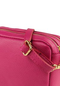 Leuchtend pinke Lederhandtasche mit strukturierter Oberfläche, ausgestattet mit einem goldfarbenen Reißverschluss und Riemendetails, die eine einfache rechteckige Form präsentiert.