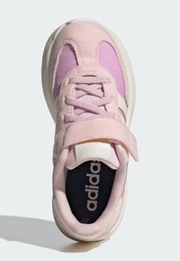 Chaussure de sport rose avec une tige en daim et en mesh, design à lacets, sangle Velcro, accents blancs et semelle intérieure noire avec logo.