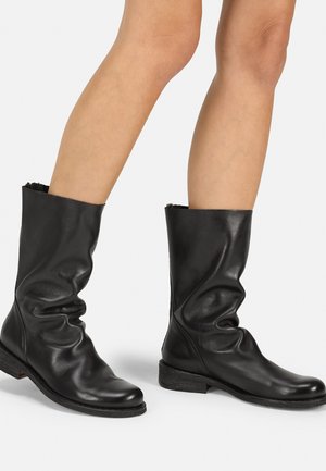 Black leather ankle boots with a slouchy design, soft texture, low heel, and smooth surface. Features no visible hardware or accents.