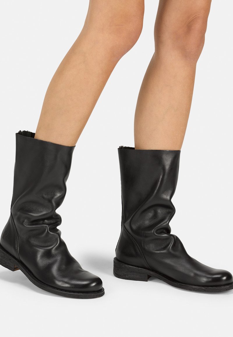 Schwarze Lederknöchelstiefel mit einem lässigen Design, weicher Textur, niedrigem Absatz und glatter Oberfläche. Verfügt über keine sichtbaren Beschläge oder Akzente.