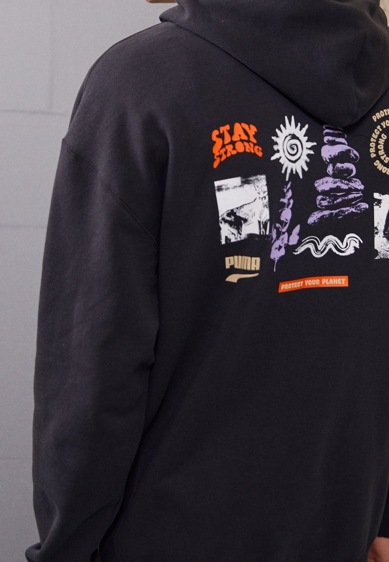Sweat à capuche noir avec des graphismes colorés sur le thème de l'environnement et de la motivation, comprenant les inscriptions "Reste Fort", un soleil, des pierres empilées, des plantes et la phrase "Protégez Votre Planète".