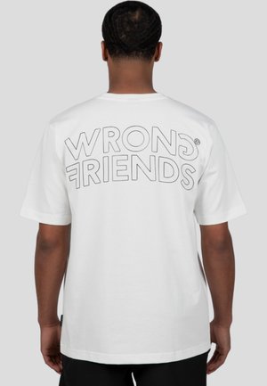 White cotton t-shirt featuring large outlined text "WRONG FRIENDS" on the back. Short sleeves and relaxed fit with a straight hem.