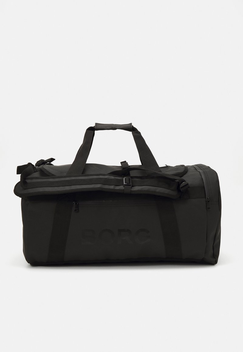 Μαύρη τσάντα ντούφελ με διπλές λαβές μεταφοράς, μαλακούς ιμάντες και μπροστινή τσέπη με φερμουάρ. Λείο υλικό, ανθεκτικό και με ανάγλυφο λογότυπο.