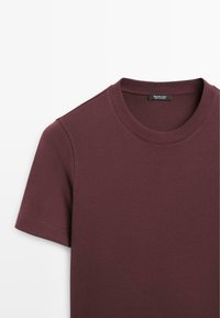 Burgundy cotton t-shirt featuring a classic crew neck and short sleeves. Smooth texture with a stitched neckline and clean seams.