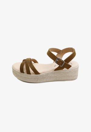 Sandalia de cuña de ante marrón con tres tiras frontales, una correa en el tobillo con hebilla plateada y suela de plataforma con textura tejida.