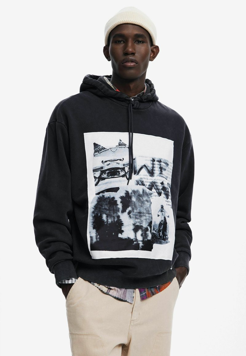 Felpa nera con stampa grafica frontale che presenta fotografie in bianco e nero. Il tessuto è morbido con una vestibilità comoda e cappuccio con cordoncino.