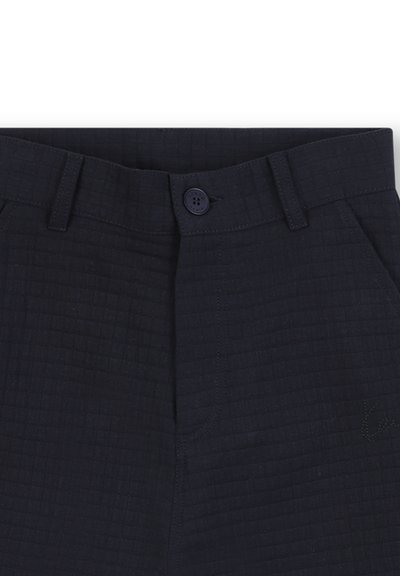 Pantalon bleu marine avec une texture matelassée, dotée d'une fermeture à bouton, de passants de ceinture et de poches avant, conçu pour une tenue décontractée.