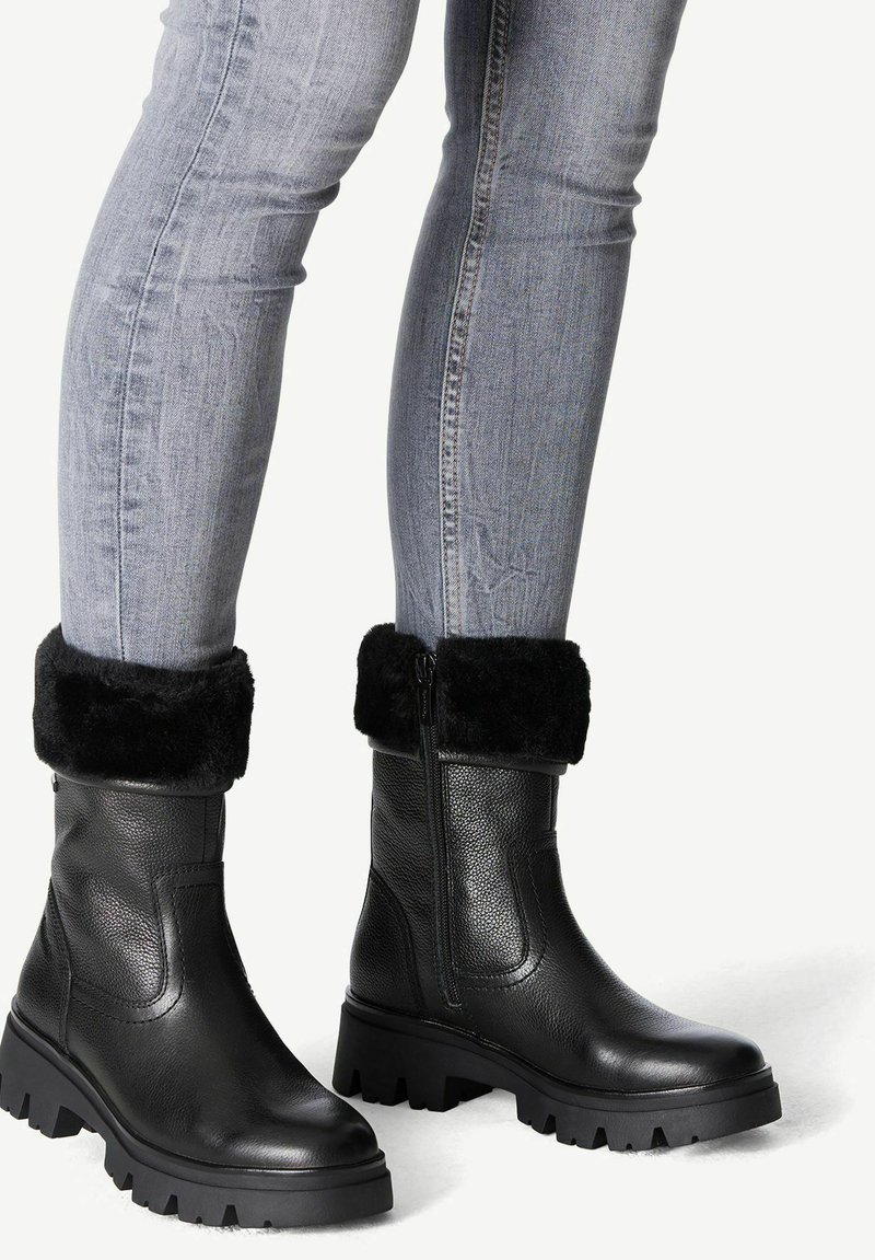 Bottes de cheville en cuir noir avec une finition texturée, un revers en fourrure et une semelle en caoutchouc épaisse. Détail zippé sur le côté pour une fonctionnalité améliorée.