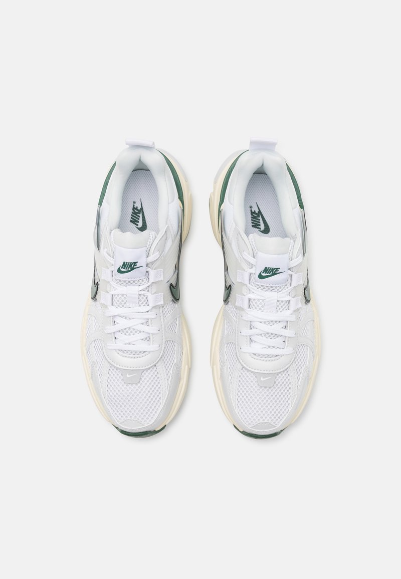 Zapatillas Nike blancas con detalles verdes, parte superior de malla, lengüeta acolchada y suela de goma gruesa. Presentan cordones y logotipo en los laterales y la lengüeta.