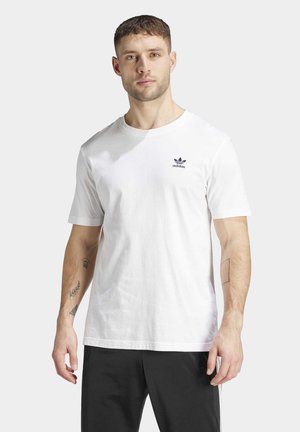 Camiseta de algodón blanca con cuello redondo y mangas cortas, con un pequeño logo negro de Adidas en el área del pecho izquierdo.