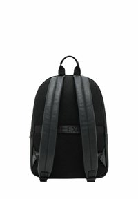 Mochila negra con un tejido de malla texturizada, acentos de cuero suave y correas acolchadas. Presenta un asa superior y cierre de cremallera.