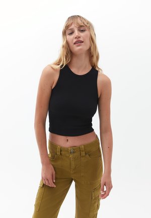 Musta ribbed crop-top, jossa on pyöreä kaula-aukko, yhdistettynä korkeavyötäröisiin oliivinvihreisiin cargo-housuihin, joissa on etupocketit ja napit.
