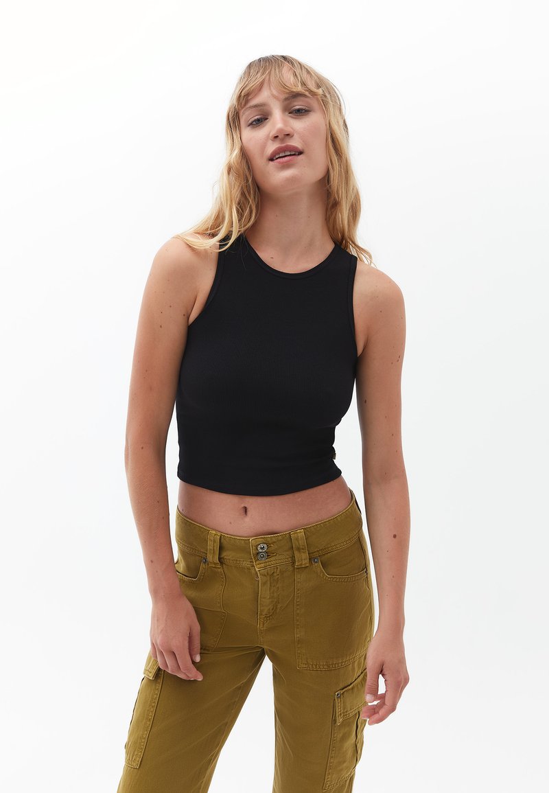 Top corto nero a coste con scollatura rotonda abbinato a pantaloni cargo verde oliva a vita alta con tasche frontali e dettagli di bottoni.