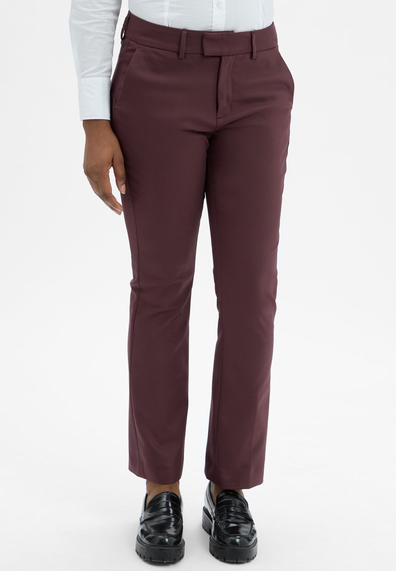 Bordeauxkleurige broek met een tailored fit, gemaakt van gladde stof. Heeft zijzakken, riemlussen en een strakke afwerking. Draagt met zwarte schoenen.