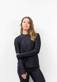 Schwarzes Langarmoberteil mit einem strukturierten Leopardenmuster, ausgestattet mit Daumenlöchern und einem lässigen Schnitt, kombiniert mit passenden Leggings.