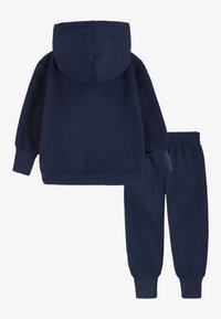 Felpa blu navy con tasca frontale e polsini elasticizzati, abbinata a pantaloni da jogging coordinati con vita elastica e caviglie elasticizzate.