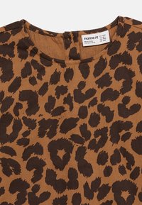 Καφέ και σκούρο καφέ ύφασμα με τύπωμα λεοπάρ, με στρογγυλή λαιμόκοψη και ραμμένη λευκή ετικέτα που δείχνει το μέγεθος και τις λεπτομέρειες της μάρκας.