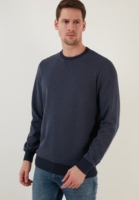 Jūras spēku melna kreklu jakas ar ribotām piedurknēm un apakšmalu, ar teksturētu virsmu un smalkām horizontālām svītrām. Saskaņots ar gaiši ziliem džinsiem.