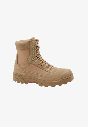 Tan taktyczne buty z zamszowej i tekstylnej cholewki, wyściełanym kołnierzem, sześcioma oczkami do sznurowania oraz solidną gumową podeszwą zapewniającą przyczepność.