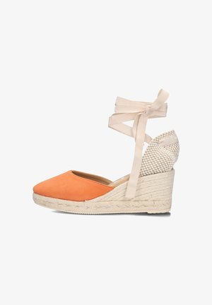 Orange suede espadrille wedge with a woven heel and beige ribbon ties, featuring a round toe and textured accent at the back.