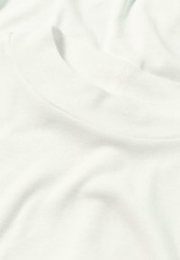 Weißes Baumwoll-T-Shirt mit Rundhalsausschnitt und glatter Textur. Der Stoff hat einen dezenten Stretch und ist in sanften Falten angeordnet.