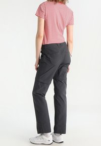 Svarta utomhusbyxor med normal passform, försedda med knäpaneler, fickor och en slät yta. Kombinerade med en kortärmad topp i röd och vit rand.