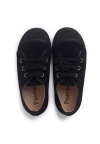 Zapatillas de lona negras con ojales dorados, cordones planos y punteras de goma, con una textura suave y con marcas en las plantillas.