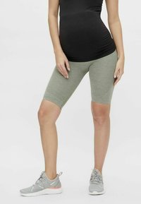 Ljusgröna cykelbyxor knälånga med en strukturerad yta, som kombineras med grå sportskor med rosa detaljer. Enkelt design.