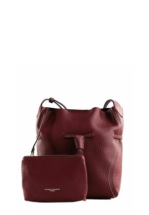 Sac seau en cuir texturé rouge foncé avec une pochette zippée assortie, tous deux arborant un logo doré, sur fond blanc.