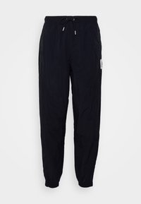 Svarta, lätta joggers med elastisk midja och dragsko. Har smalnande mudd och subtil textur. Inkluderar logotypmärke på sidan.